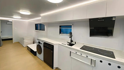 Modern kitchen with white cabinets, black appliances, and a light-colored floor inside the SX-3 space capsule pod.