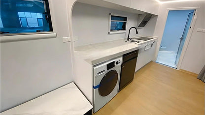 Compact kitchen with washing machine, sink, and window inside AR-3 Extended Apple Cabin living space.