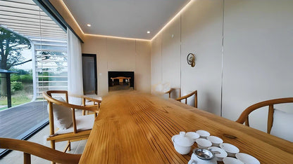 Modern interior of Extended Apple Cabine AP-3 with a long wooden dining table and chairs near a large window.
