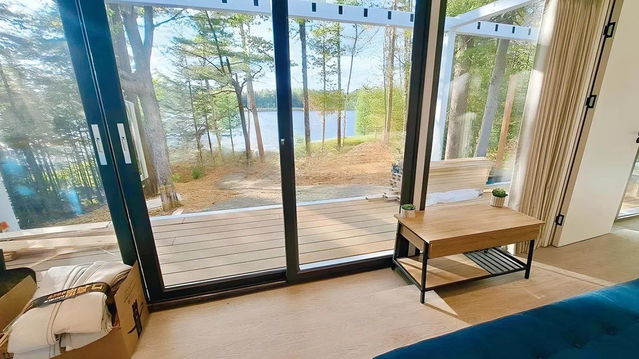 Living room of AP-3 Extended Apple Cabin with large windows overlooking a lake and forest