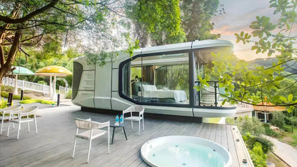 Modern modular SX-2 flow space capsule pod with outdoor furniture and a hot tub in a natural glamping setting