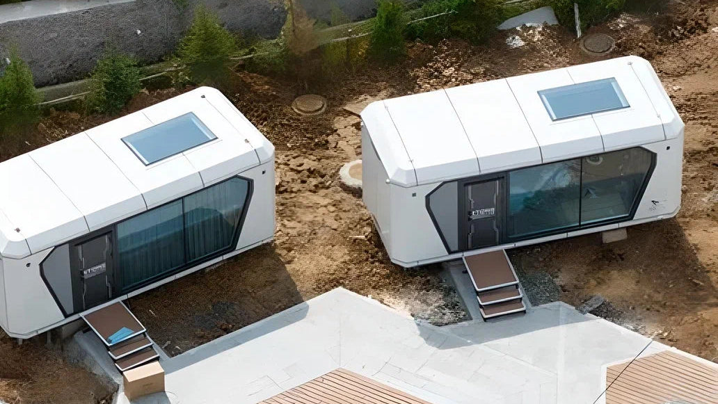 Two modern, white modular AP-1 Compact Apple Cabin buildings with glass windows on a construction site.