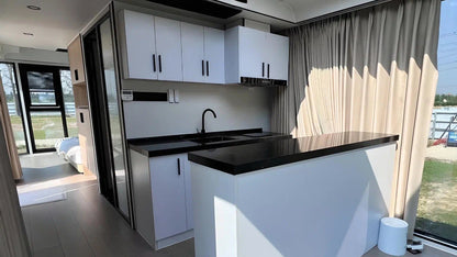 Modern kitchen with white cabinets, black countertops, and a large window inside SX-2 flow space capsule modular pod.