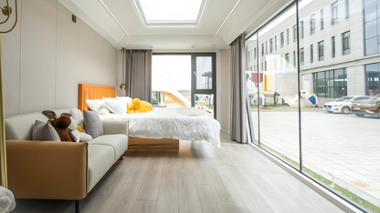 Modern bedroom inside the AP-2 Balanced Apple Cabin modular unit with a large window view of an urban street.