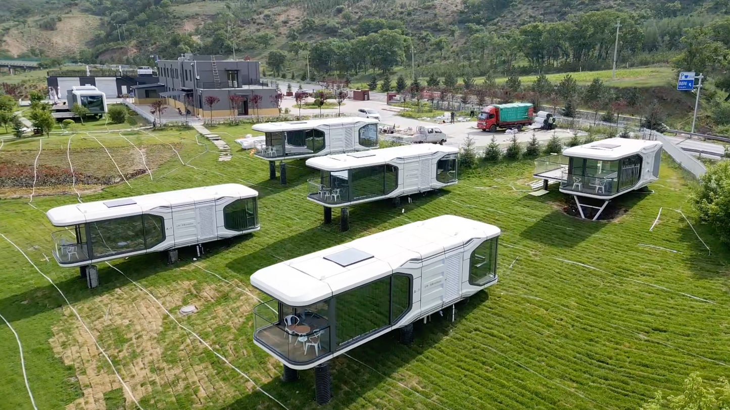 Modular SX-3 vista space capsule buildings on wheels arranged in a field with a scenic background