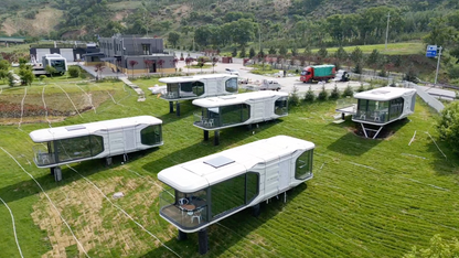 Modular SX-3 vista space capsule buildings on wheels arranged in a field with a scenic background