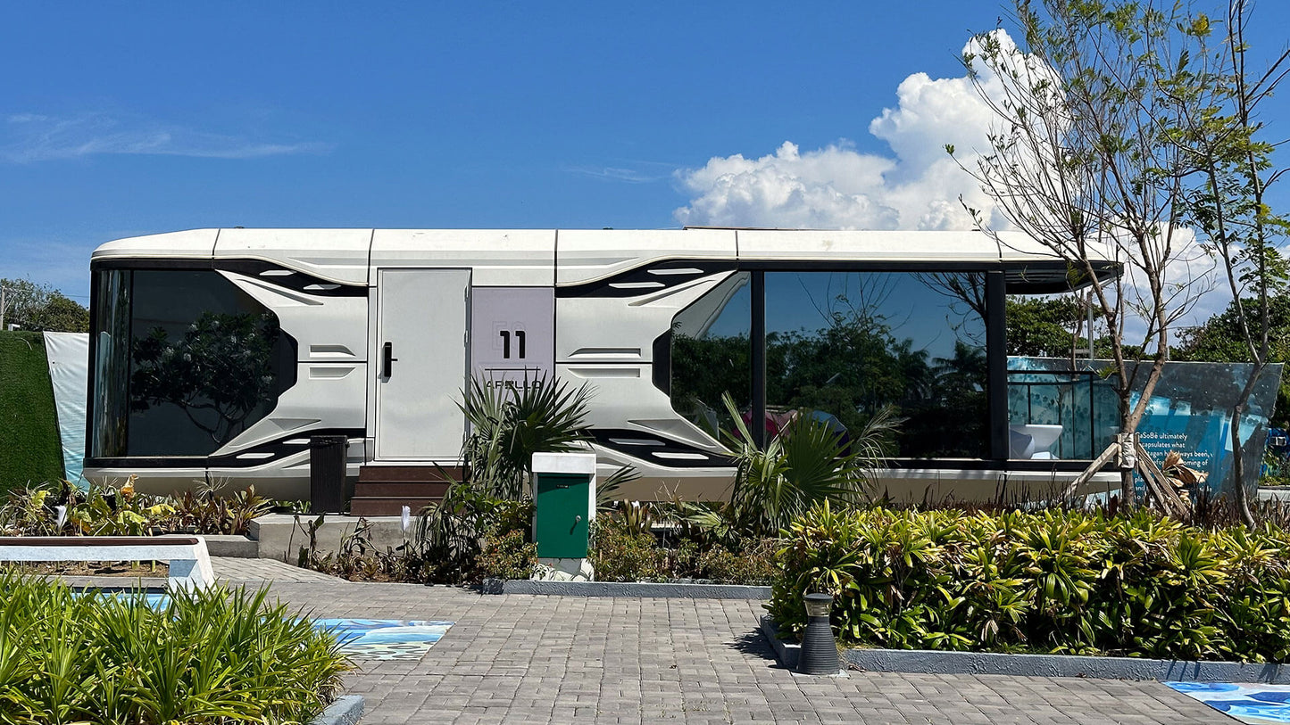 Modern SX-3 vista space capsule is parked like an RV in a scenic outdoor setting with plants and a clear sky.