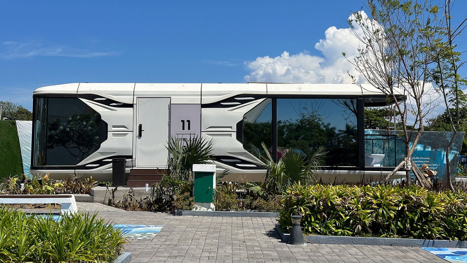 Modern SX-3 vista space capsule is parked like an RV in a scenic outdoor setting with plants and a clear sky.