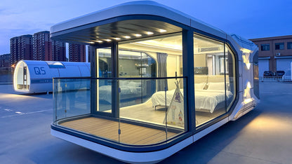 Modern, transparently-walled living module pod SX-2 Flow space capsule on a rooftop at dusk.
