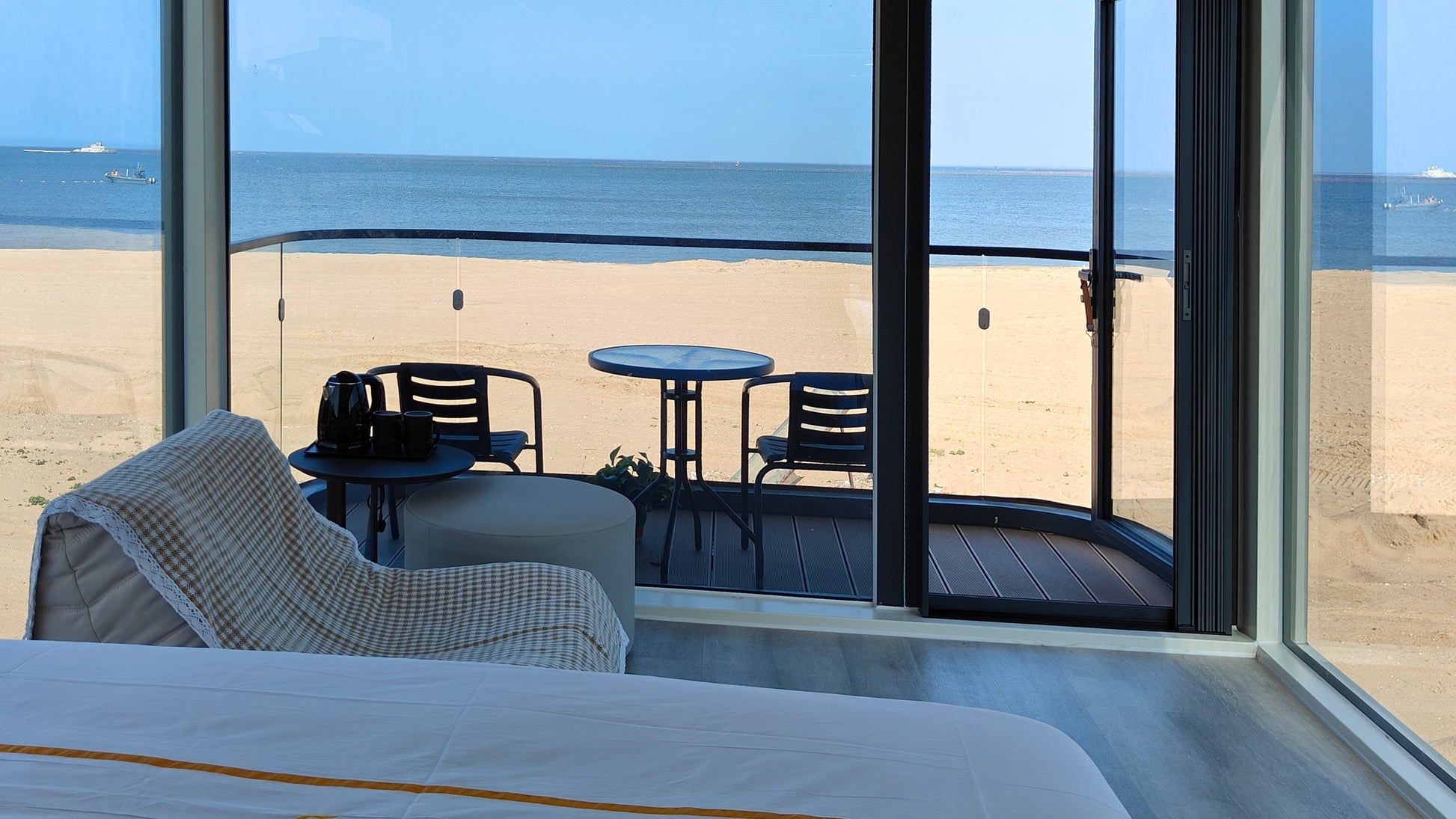Room of SX-1 Lite Space Capsule with a large window view of a beach and ocean.